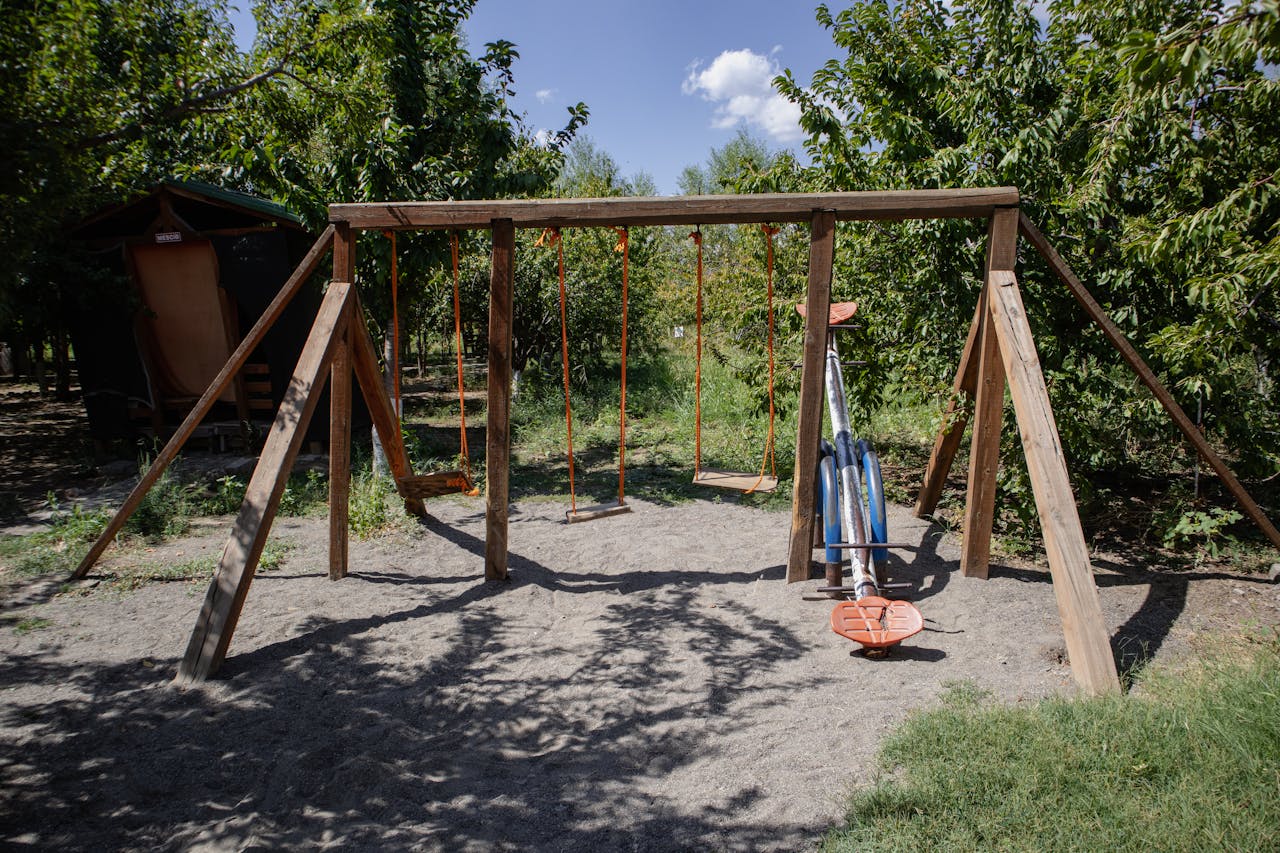 Peaceful playground with swings and a seesaw surrounded by trees in Bingöl, Türkiye.
